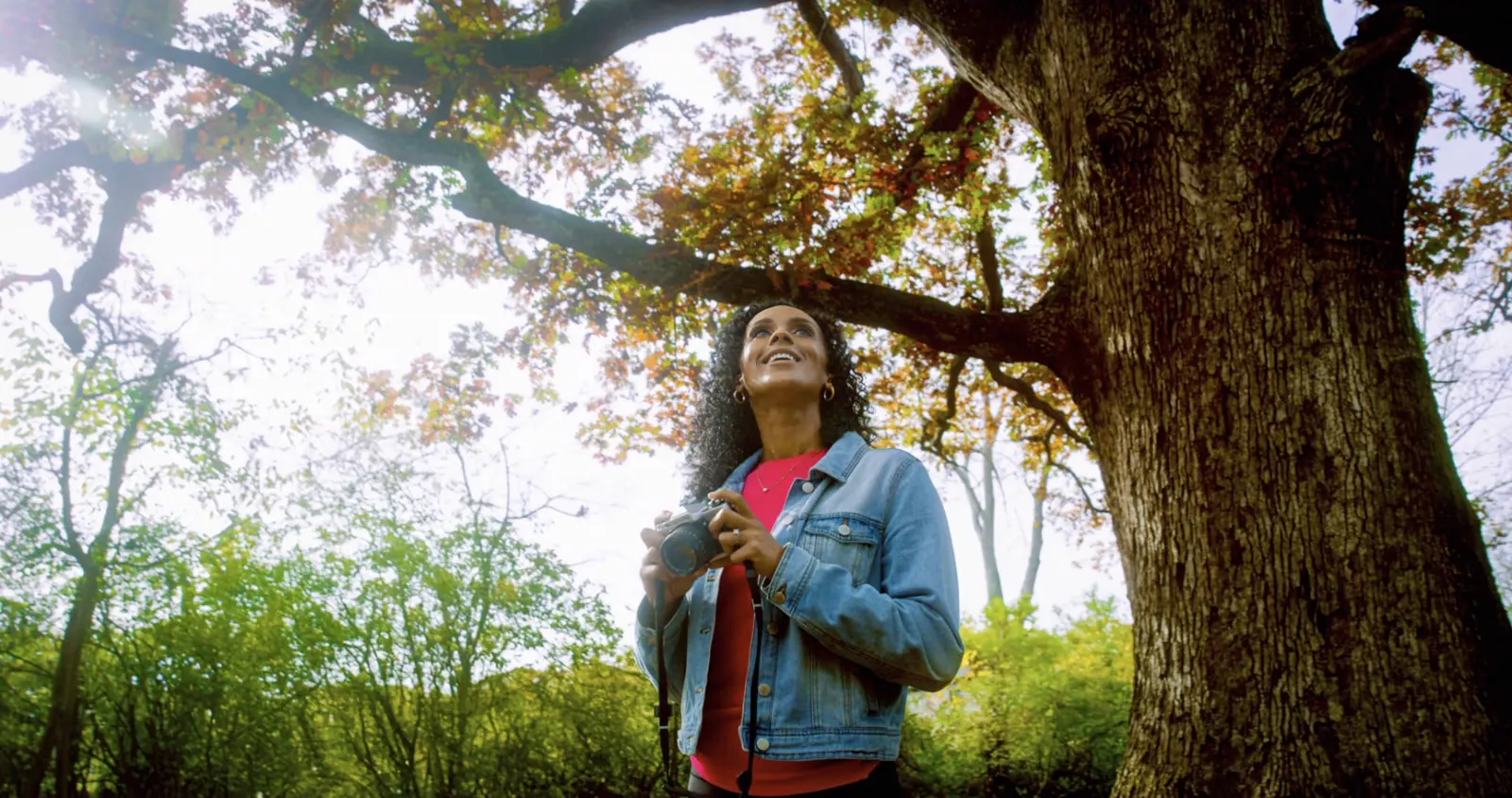 Woman enjoying a peaceful moment outdoors beneath a large tree